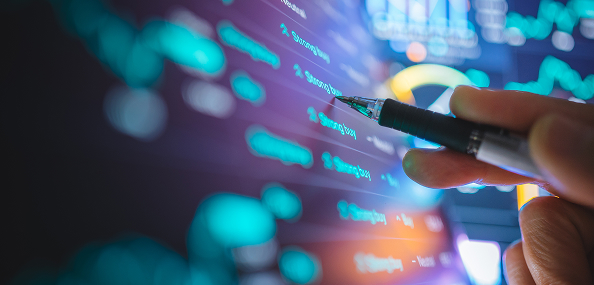 Analyst reviewing financial data with pen on digital display